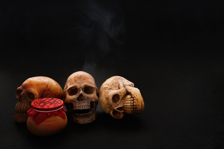 Still life of human skull and spell spirit pot on black backgroundの写真素材