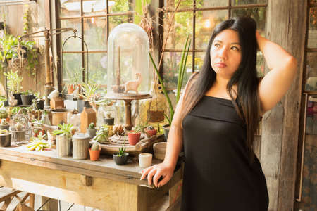 Woman in black dress standing in cactus garden fun of trees and flowers an day time with happy face/Woman in cactus garden with happy faceの写真素材