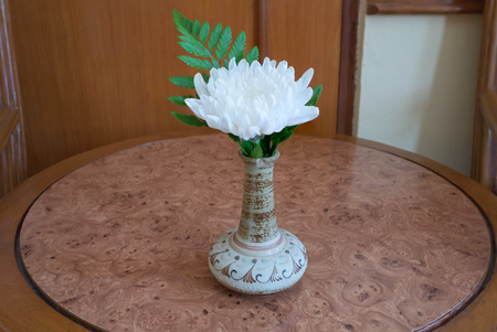 White flower with green leaf in bouquet put in ceramic vase on brown wooden table/White flower in vase on wooden table top viewの写真素材