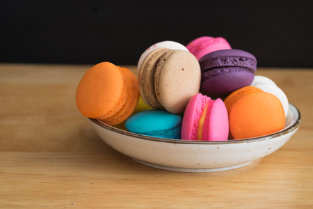 colorful macaroon in white ceramic plate with all flavors on wooden table/colorful macaroon in ceramic plateの写真素材
