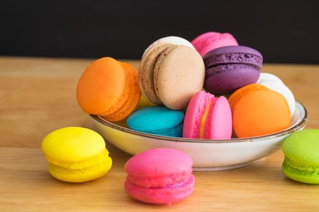 colorful macaroon in white ceramic plate with all flavors on wooden table/colorful macaroon in ceramic plateの写真素材