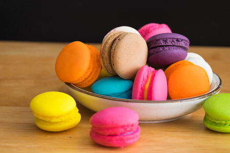 colorful macaroon in white ceramic plate with all flavors on wooden table/colorful macaroon in ceramic plateの写真素材