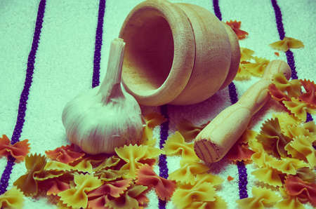 Wooden mortar filled with Italian pasta with garlic ingredients for preparationの写真素材