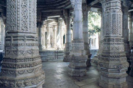jain architecture: jainism temple in Ranakpur, Rajasthan, India. Glimpse trough marbre pillars of the adinatha jainism temple, that has 1444 marble pillars. Picture with wide depth of field. On foreground pillars in shadow. On background enlightened pillaのeditorial素材