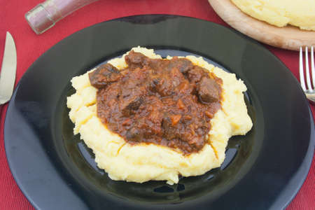wild boar stew on polenta  view from above close-up on black  dish,italian foodの写真素材