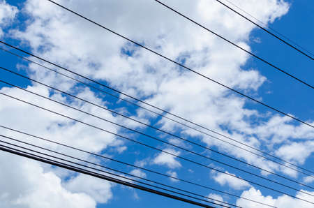 Power transmission lines across a blue sky and cloud.の写真素材