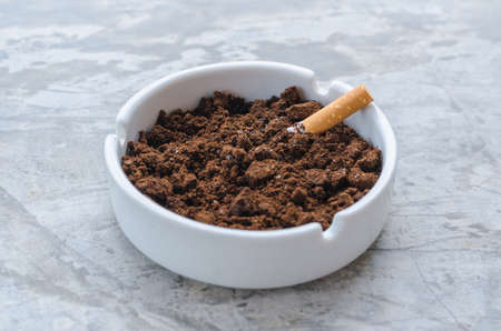 The ceramic ashtray contain coffee ground on concrete floor for protection fire from cigarette.の写真素材