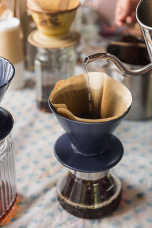 Hand holding pot pouring hot water to filter on dripper coffee. Selective Focus.の写真素材