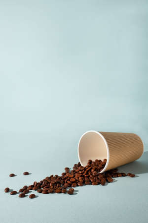 Paper cup of coffee with coffee beans on blue background. Side view. Take away cup.