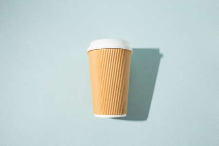 Paper cup of coffee on blue background. Top view. Take away cup.