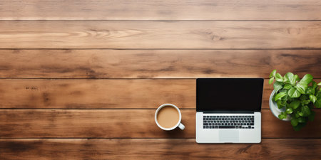 Top view of modern workspace with laptop, coffee cup and plant on wooden background.の素材
