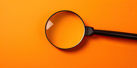 Magnifying glass on orange background. View from above. Close-up.の素材
