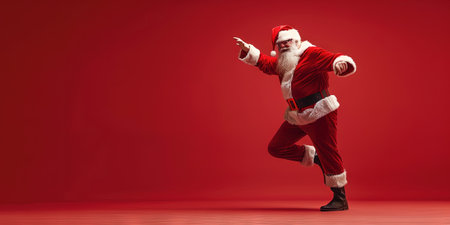 Full length portrait of a santa claus dancing against red backgroundの素材