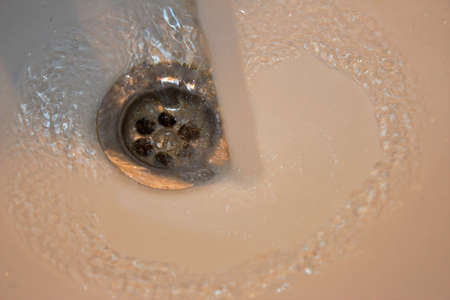 Flowing water in a bathroom sink, close-up.の写真素材