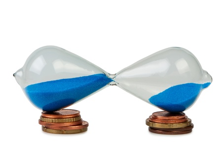 Sand-glass on coins isolated white.