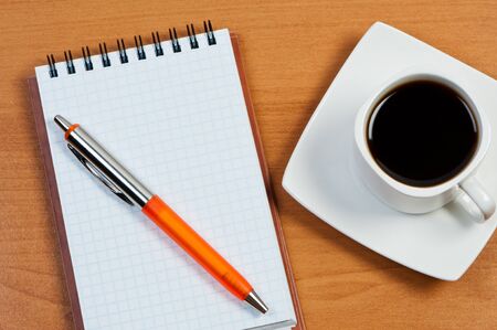 Notebook with pen and coffee on table top view.の写真素材