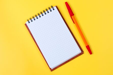 Notepad and pen on yellow background.の写真素材