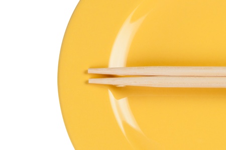 Yellow plate with chopsticks close up.