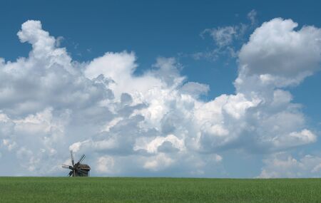 Old wooden windmill against sky with clouds の写真素材