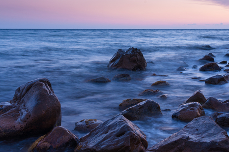 Sunset on sea. In foreground big boulders.の写真素材