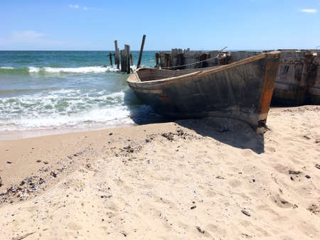 Wooden fishing boat on shore. In background sea and ruined pier.の写真素材
