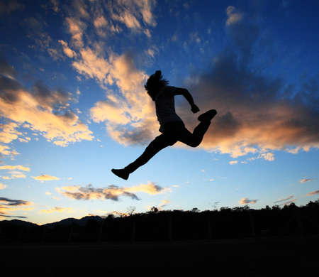 man jumping againts dark blue sky background  