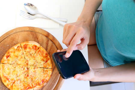 female using mobile phone on food table の写真素材