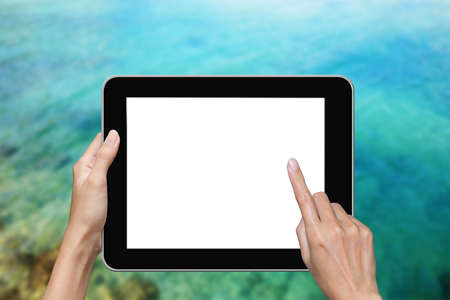 hand using tablet with sea backgroundの写真素材