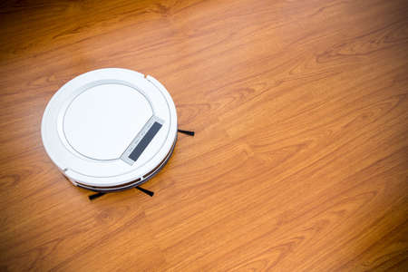 Robotic vacuum cleaner on laminate wood floor.の写真素材