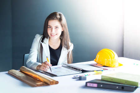 Smiling young woman sitting on office desk and looking to camera.の写真素材