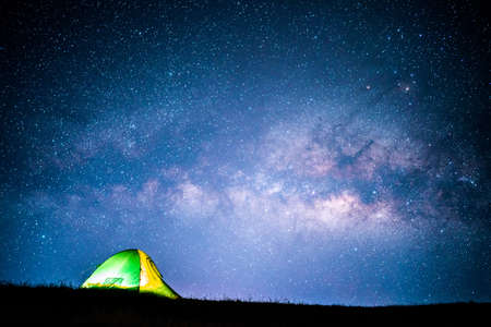 Milky way over green tent on hill.の写真素材