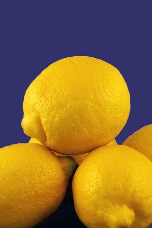 A pile of yellow lemons against a blue backgroundの写真素材