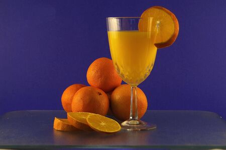 Oranges and orange juice against a blue backgroundの写真素材
