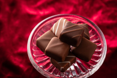 Chocolate candies in a glass bowl on a red background.の写真素材
