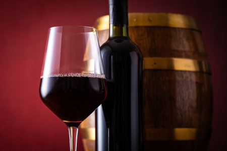 Bottle of red wine, glass and barrel on a red backgroundの写真素材
