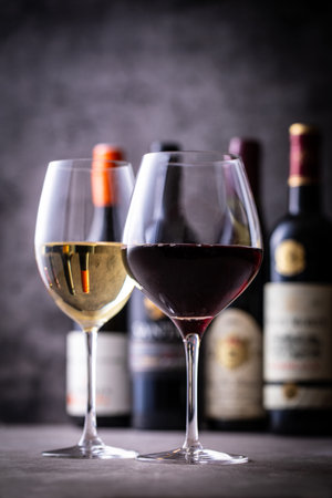 Bottles and glasses of red and white wine on a dark background