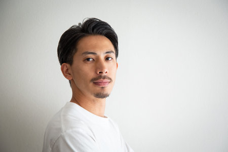 Portrait of a young asian man looking at camera against white background