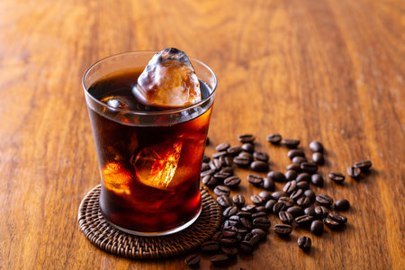 Glass of cola with ice cubes on wooden table