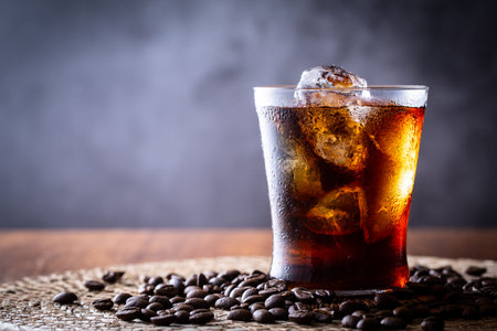 Cola with ice cubes on a wooden table background.
