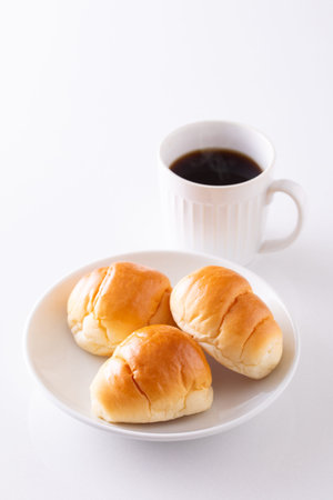 Cup of coffee and bread rolls on white background, close up