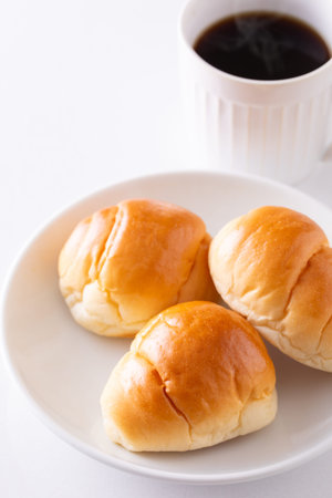 Bread buns and a cup of coffee on white background.