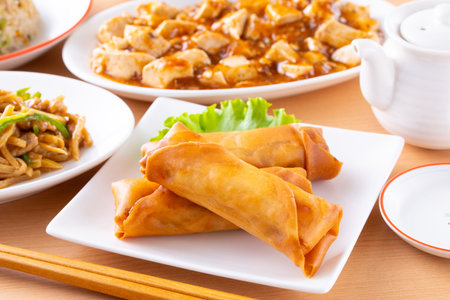 Fried spring rolls with vegetables and sauce in white plate on wooden table