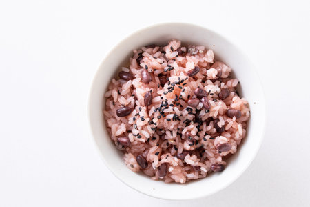 Bowl of brown rice with black sesame seeds on white backgroundの写真素材