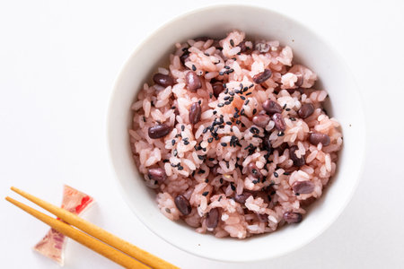 Bowl of rice with black beans and chopsticks on white backgroundの写真素材