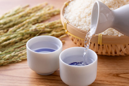 Pouring sake and rice in bamboo basket on wooden backgroundの写真素材