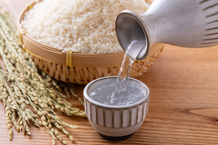 Pouring rice into a bowl with rice grains on wooden background.の写真素材