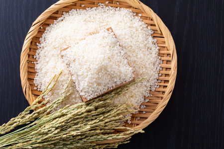 Rice in a basket on a black wooden table, top viewの写真素材