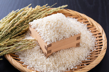 Rice in a bamboo sieve on black wooden table, stock photoの写真素材