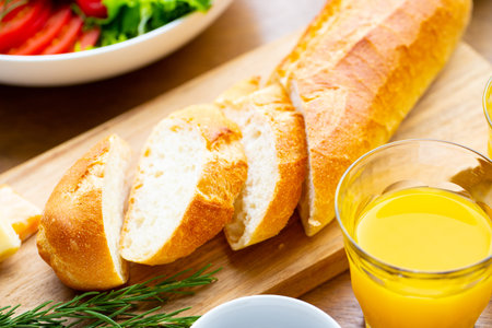 Breakfast with fresh bread, juice and vegetable salad on wooden table
