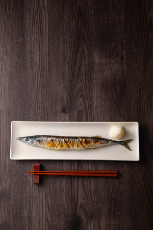 Saba fish on a white plate with chopsticks on a wooden background